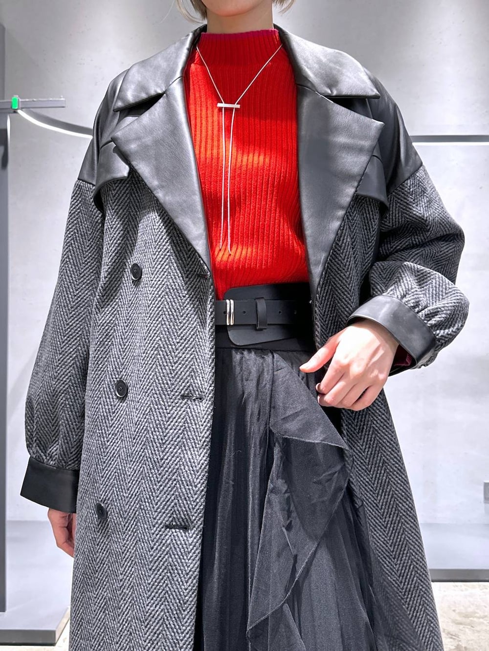 グレー系のチェスターコート、レッド系のニット/セーター、ブラック系のブーツを着用したレディースの冬コーディネートの5枚目の写真