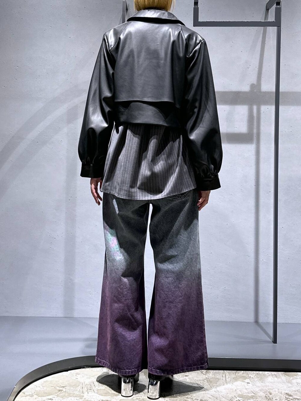 パープル系のデニムパンツ、ブラック系のブーツ、ブラック系のブルゾンを着用したレディースの秋コーディネートの3枚目の写真