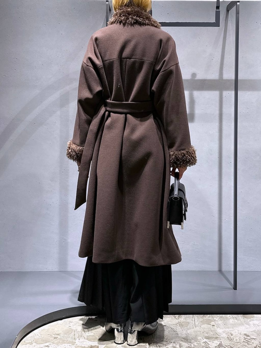 ホワイト系のニット/セーター、シルバー系のブーツ、ブラック系のショルダーバッグを着用したレディースの冬コーディネートの3枚目の写真