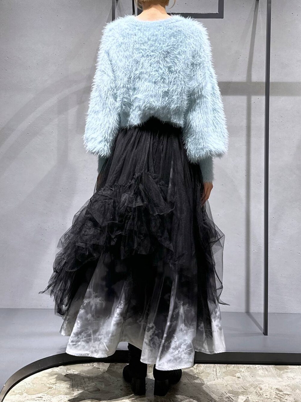 グリーン系のニット/セーター、ブラック系のブーツ、ブラック系のスカートを着用したレディースの冬コーディネートの3枚目の写真