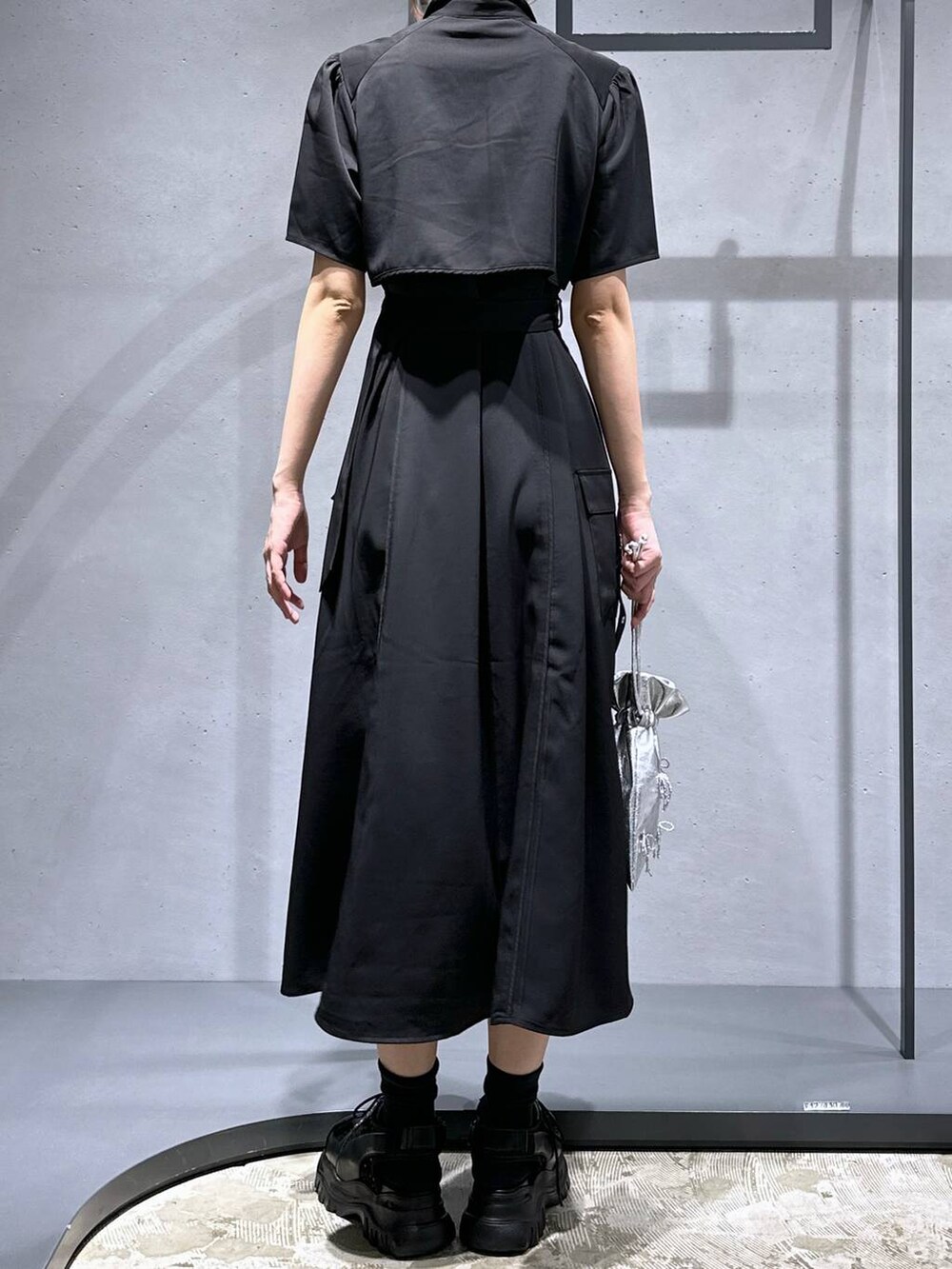 ブラック系のサンダル、ブラック系のワンピース、シルバー系のショルダーバッグを着用したレディースの夏コーディネートの3枚目の写真