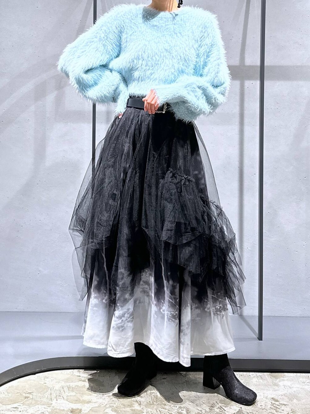 グリーン系のニット/セーター、ブラック系のブーツ、ブラック系のスカートを着用したレディースの冬コーディネートの4枚目の写真