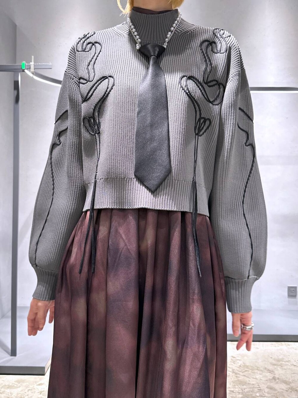 ブラック系のネクタイ、シルバー系のブーツ、グレー系のニット/セーターを着用したレディースの冬コーディネートの5枚目の写真