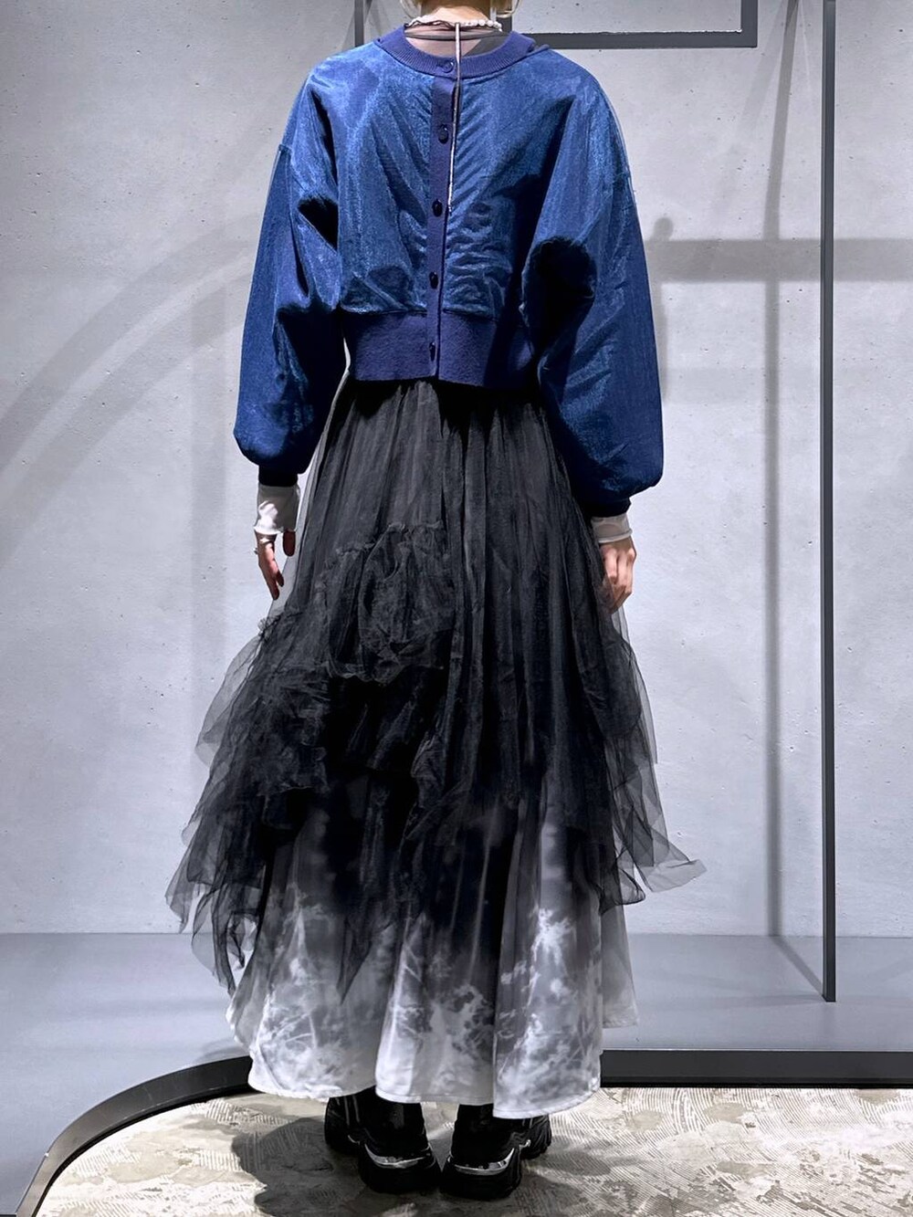 ブラック系のネクタイ、ブルー系のカーディガン/ボレロ、ブラック系のスカートを着用したレディースの冬コーディネートの3枚目の写真