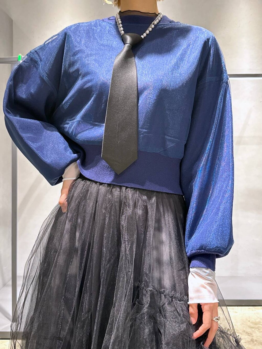 ブラック系のネクタイ、ブルー系のカーディガン/ボレロ、ブラック系のスカートを着用したレディースの冬コーディネートの5枚目の写真