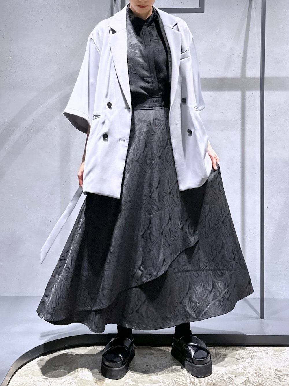 ブラック系のサンダル、ブラック系のスカート、グレー系のテーラードジャケットを着用したレディースの春コーディネートの4枚目の写真