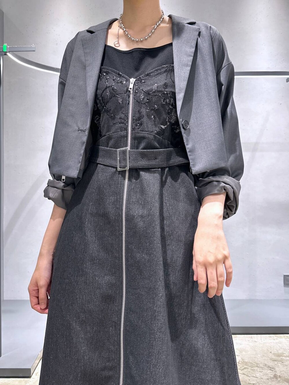 グレー系のテーラードジャケット、ブラック系のパンプス、パープル系のスラックスを着用したレディースの夏コーディネートの5枚目の写真