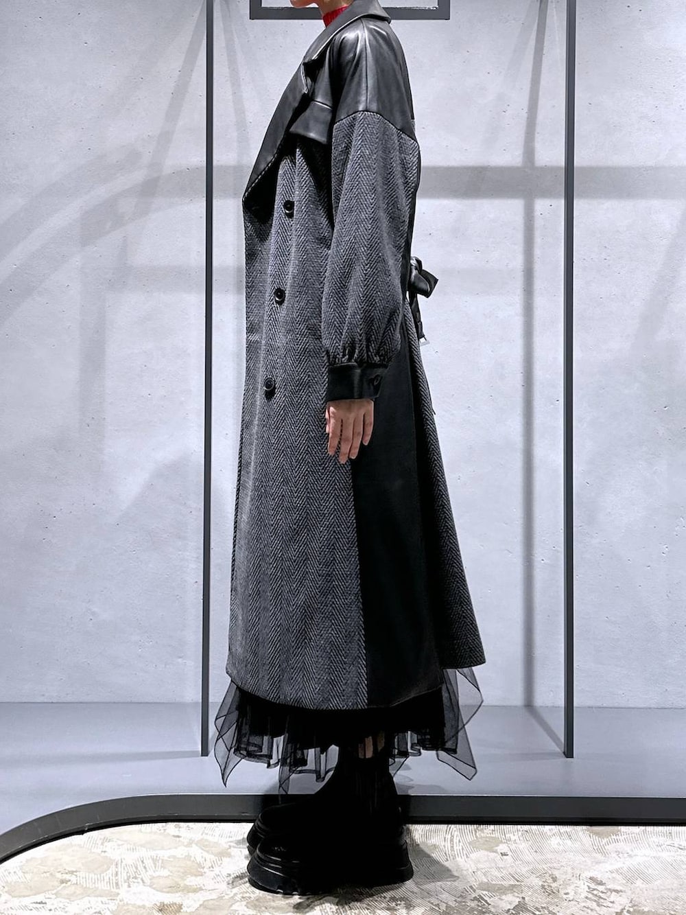 グレー系のチェスターコート、レッド系のニット/セーター、ブラック系のブーツを着用したレディースの冬コーディネートの2枚目の写真