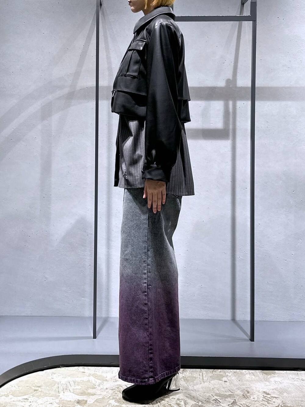 パープル系のデニムパンツ、ブラック系のブーツ、ブラック系のブルゾンを着用したレディースの秋コーディネートの2枚目の写真