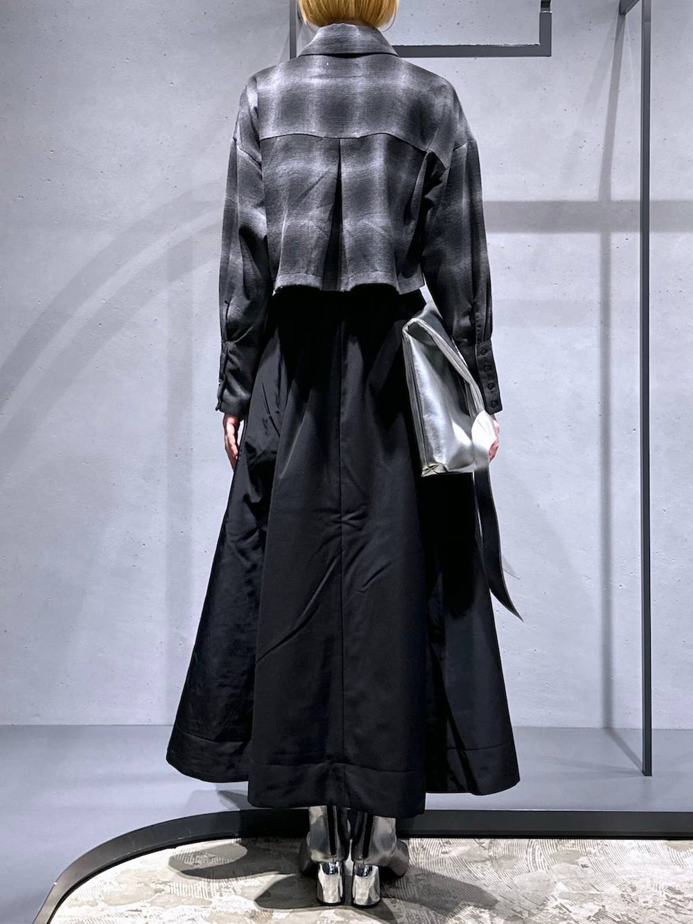 シルバー系のブーツ、ブラック系のスカート、シルバー系のトートバッグを着用したレディースの秋コーディネートの3枚目の写真