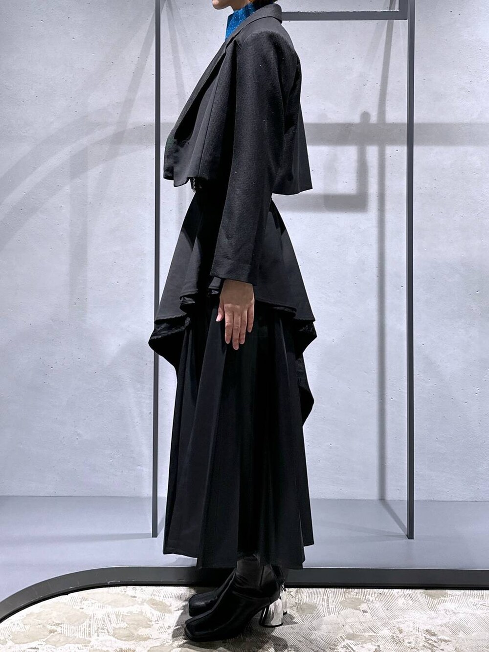 ブラック系のスカート、ブルー系のニット/セーター、ブラック系のブーツを着用したレディースの秋コーディネートの2枚目の写真