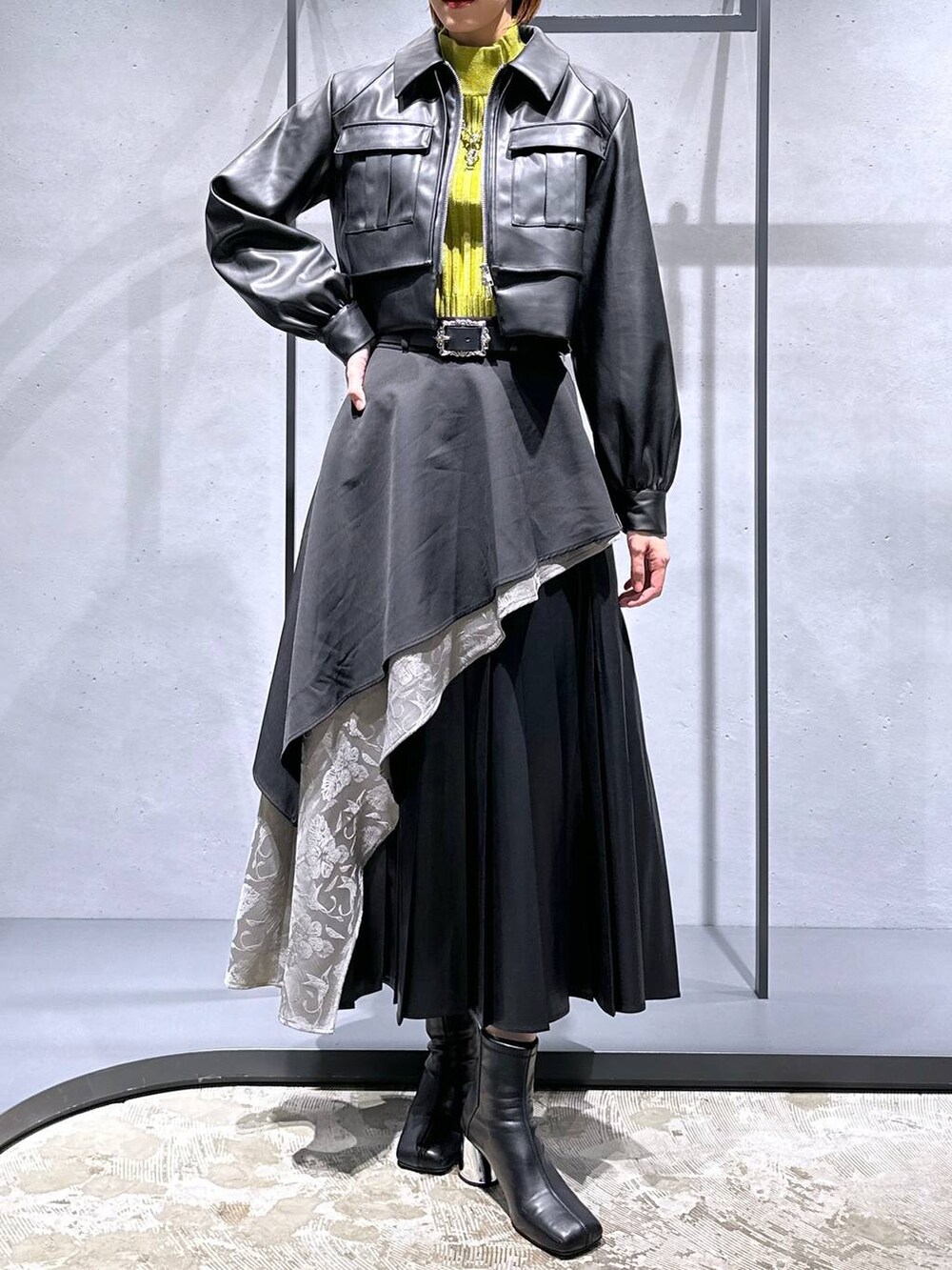 グレー系のスカート、イエロー系のニット/セーター、ブラック系のブーツを着用したレディースの秋コーディネートの4枚目の写真