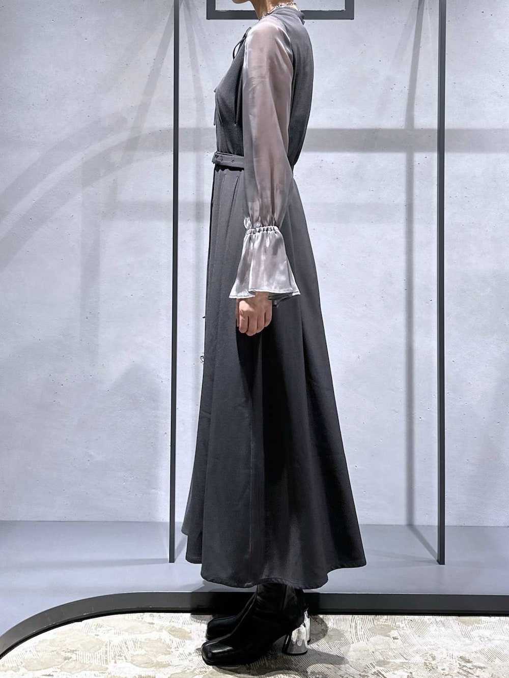 シルバー系のハンドバッグ、ブラック系のブーツ、グレー系のドレスを着用したレディースの秋コーディネートの3枚目の写真