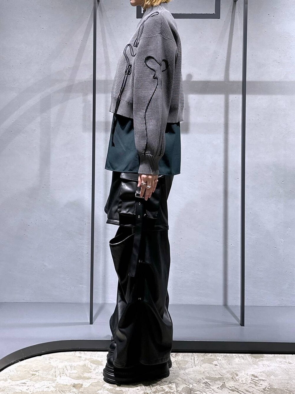 ブラック系のカーゴパンツ、ブラック系のブーツ、グレー系のニット/セーターを着用したレディースの冬コーディネートの2枚目の写真