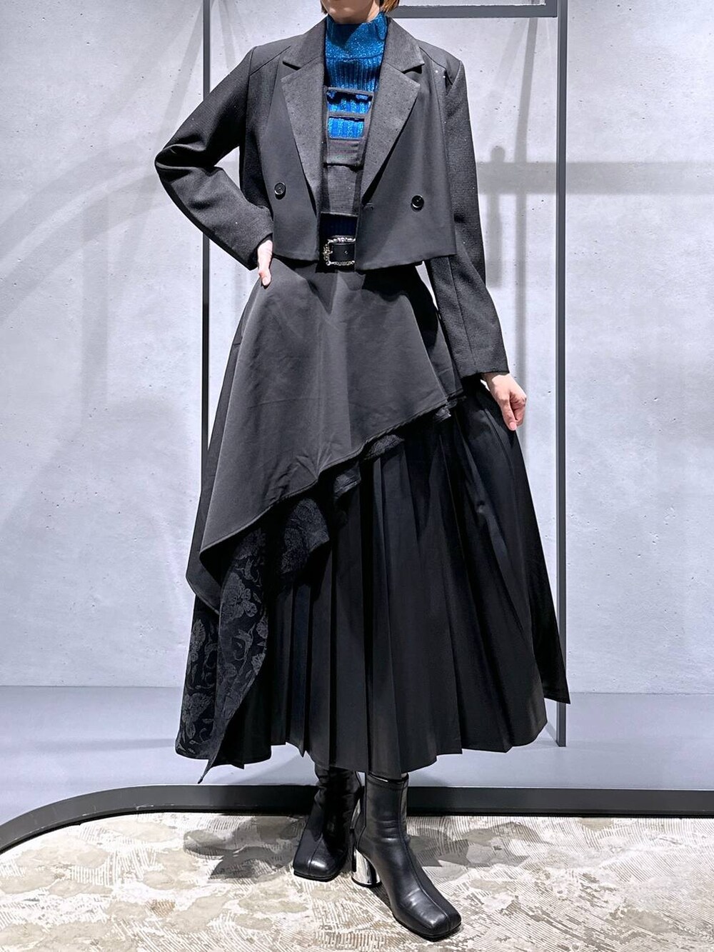 ブラック系のスカート、ブルー系のニット/セーター、ブラック系のブーツを着用したレディースの秋コーディネートの4枚目の写真