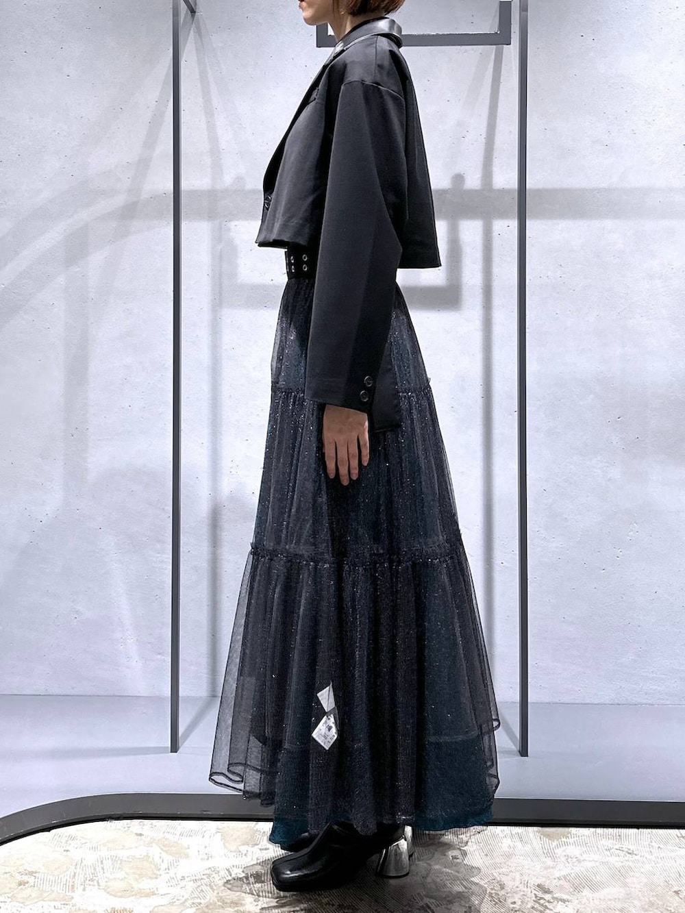 グリーン系のスカート、ブラック系のブーツ、ブラック系のシャツ/ブラウスを着用したレディースの秋コーディネートの2枚目の写真