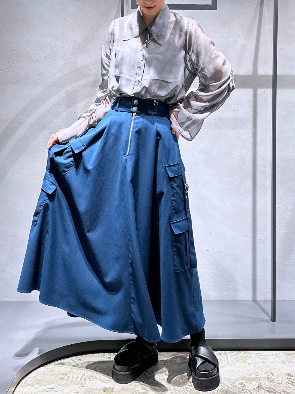 ブラック系のサンダル、ブルー系のスカート、シルバー系のネックレスを着用したレディースの春コーディネートの4枚目の写真