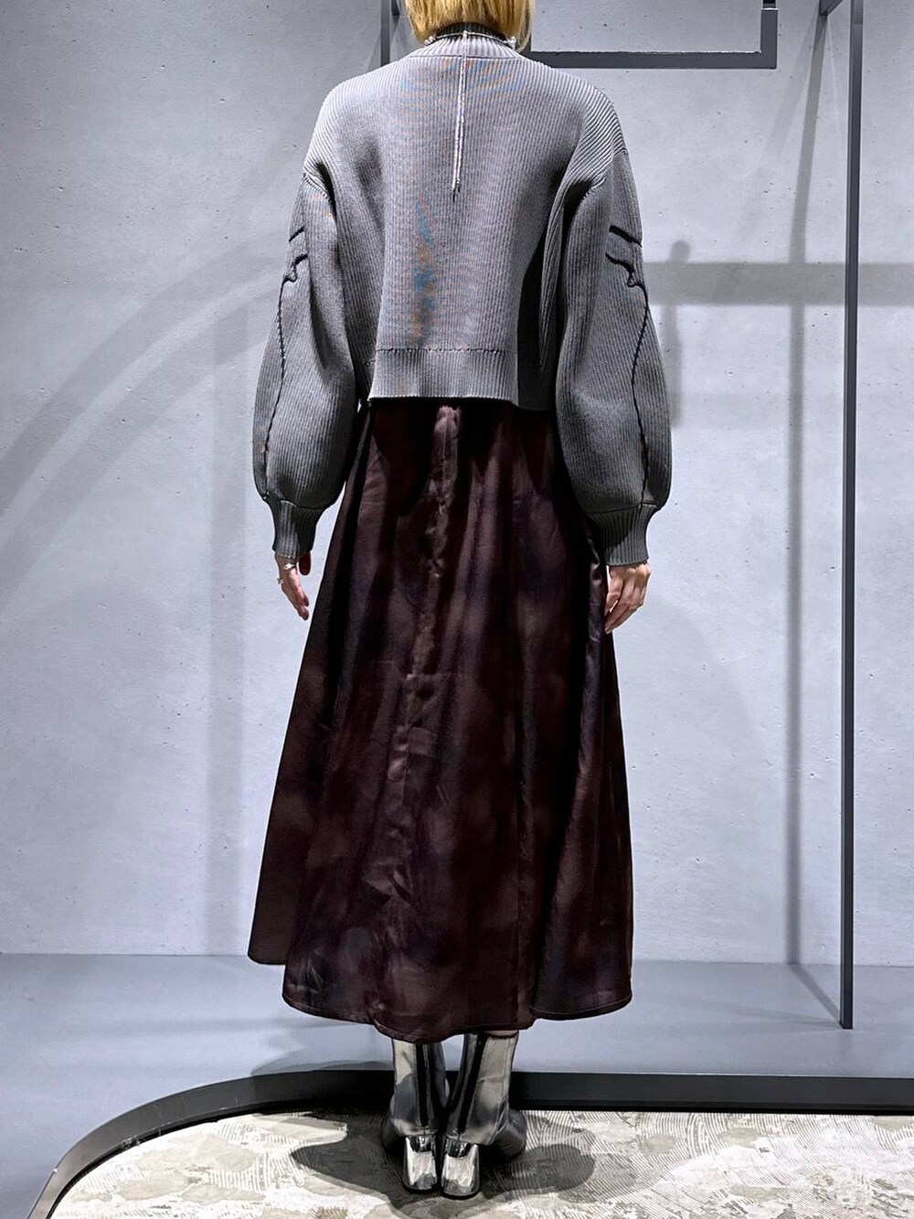 ブラック系のネクタイ、シルバー系のブーツ、グレー系のニット/セーターを着用したレディースの冬コーディネートの3枚目の写真