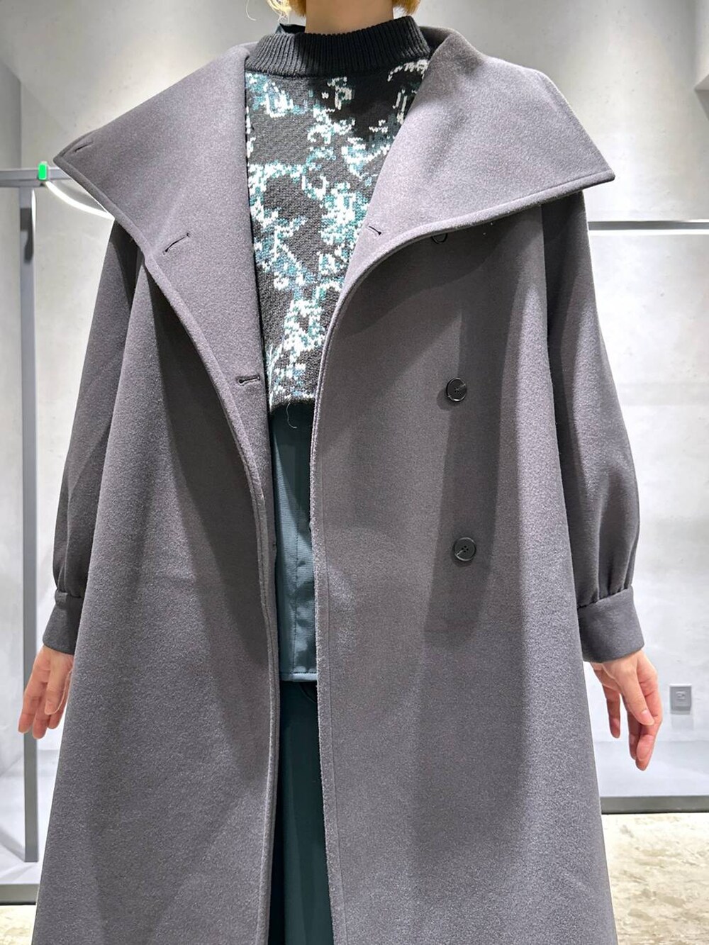 グレー系のチェスターコート、ブラック系のニット/セーター、グリーン系のシャツ/ブラウスを着用したレディースの秋コーディネートの5枚目の写真