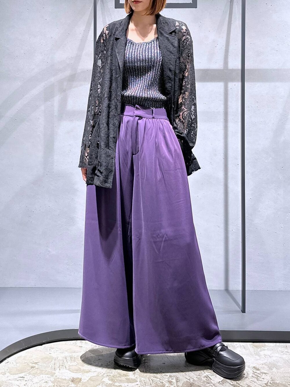 ブラック系のタンクトップ、パープル系のスラックス、ブラック系のブーツを着用したレディースの夏コーディネートの4枚目の写真