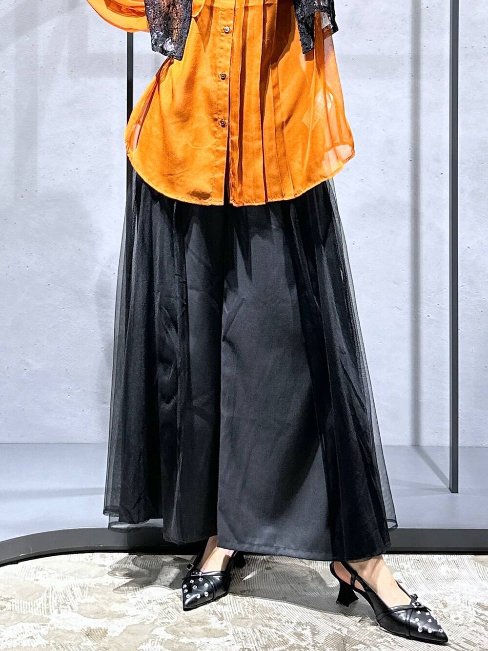 オレンジ系のシャツ/ブラウス、ブラック系のシャツ/ブラウス、ブラック系のパンプスを着用したレディースの夏コーディネートの6枚目の写真