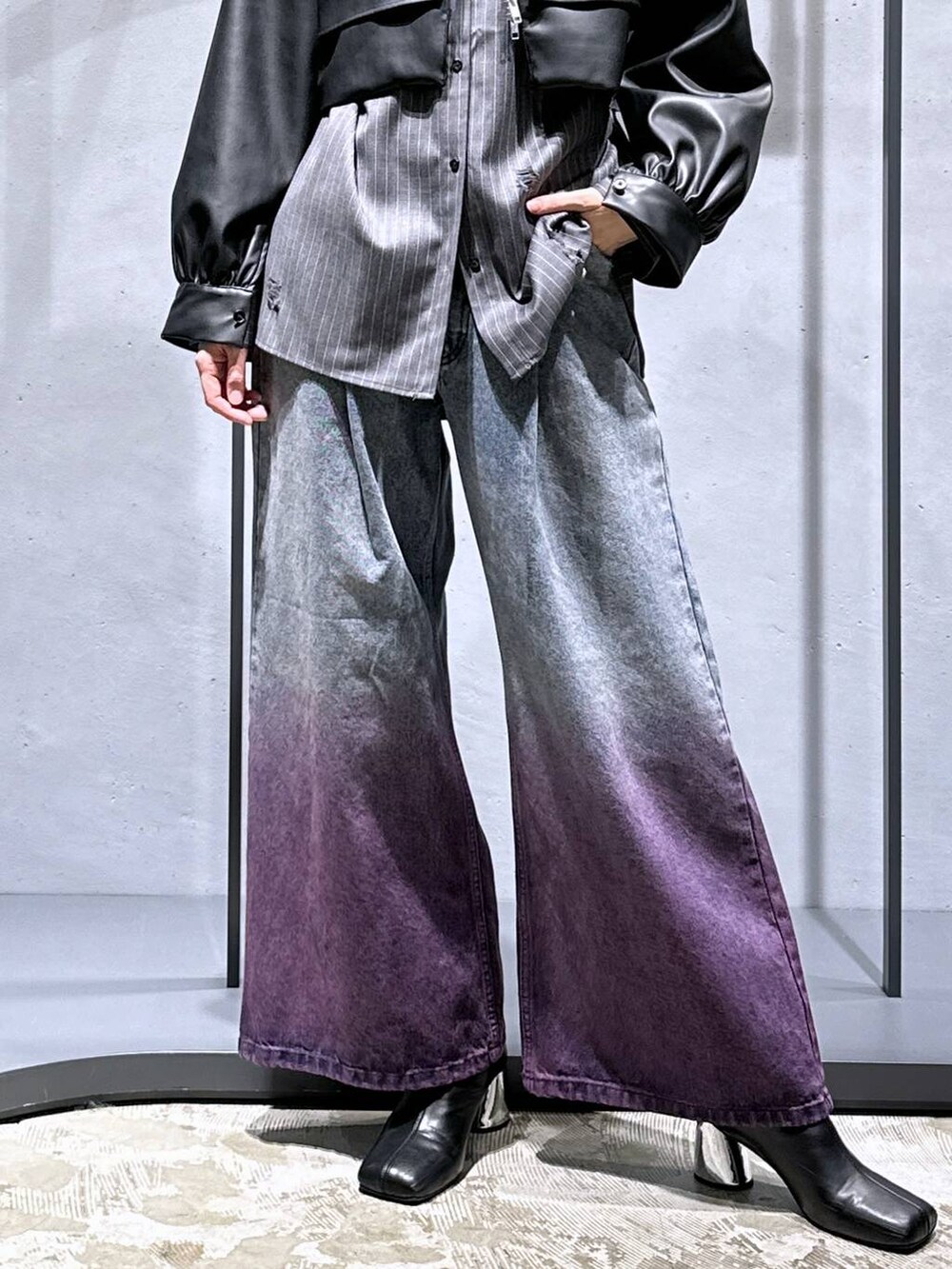 パープル系のデニムパンツ、ブラック系のブーツ、ブラック系のブルゾンを着用したレディースの秋コーディネートの6枚目の写真