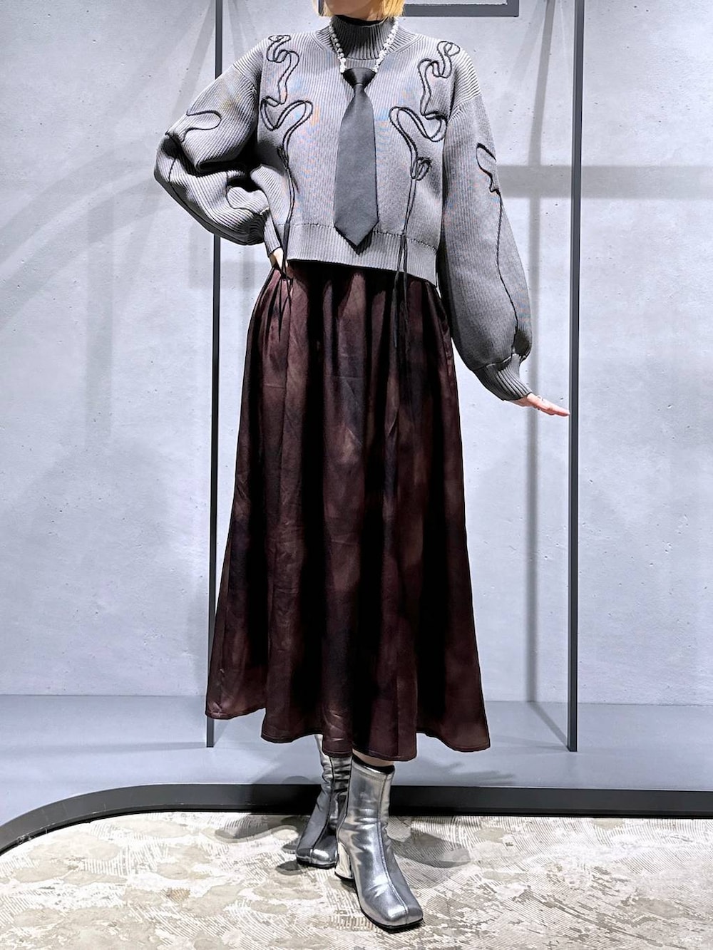 ブラック系のネクタイ、シルバー系のブーツ、グレー系のニット/セーターを着用したレディースの冬コーディネートの4枚目の写真