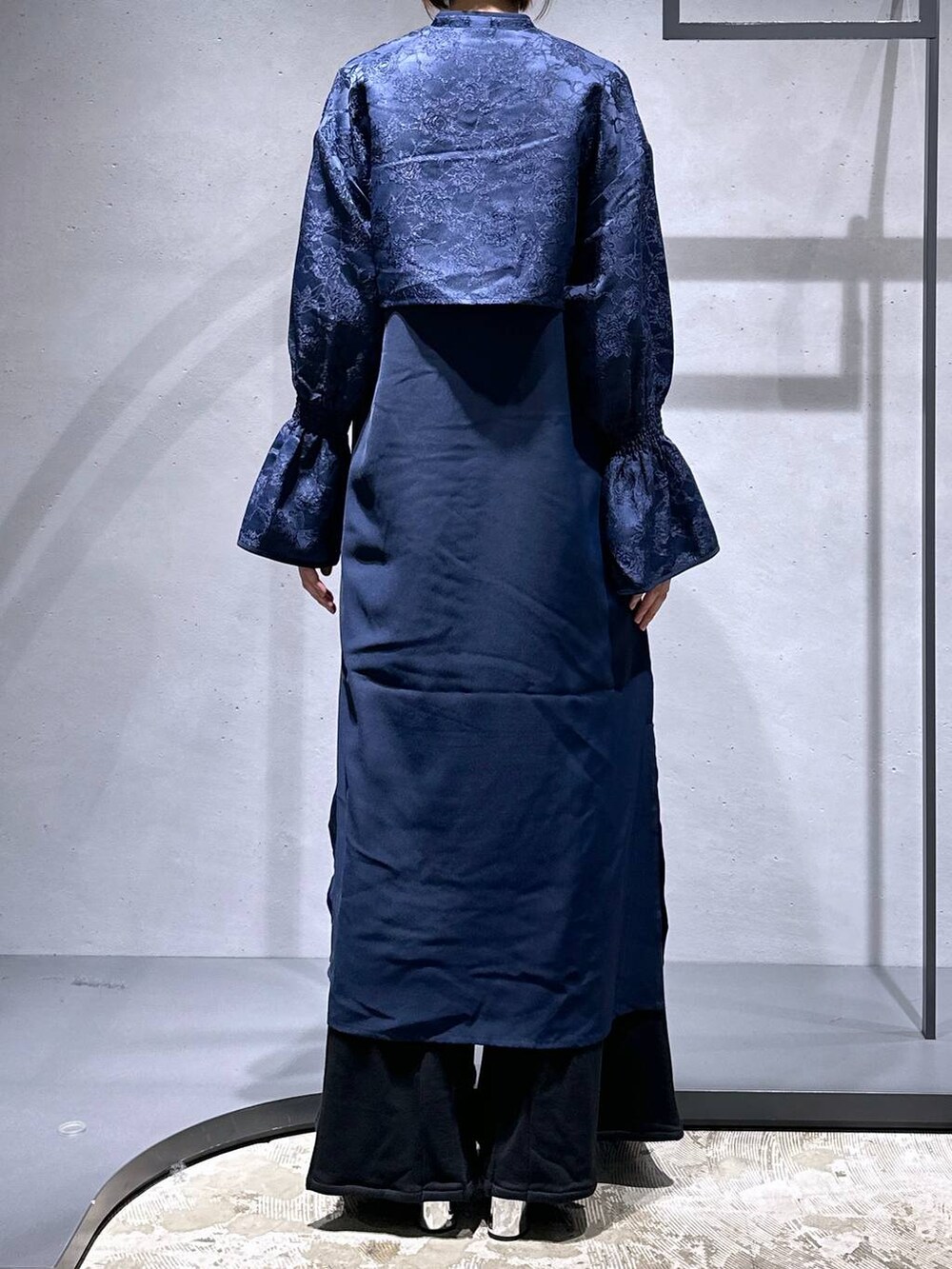 ブラック系のブーツ、ブラック系のスウェットパンツ、ブルー系のワンピースを着用したレディースの秋コーディネートの3枚目の写真