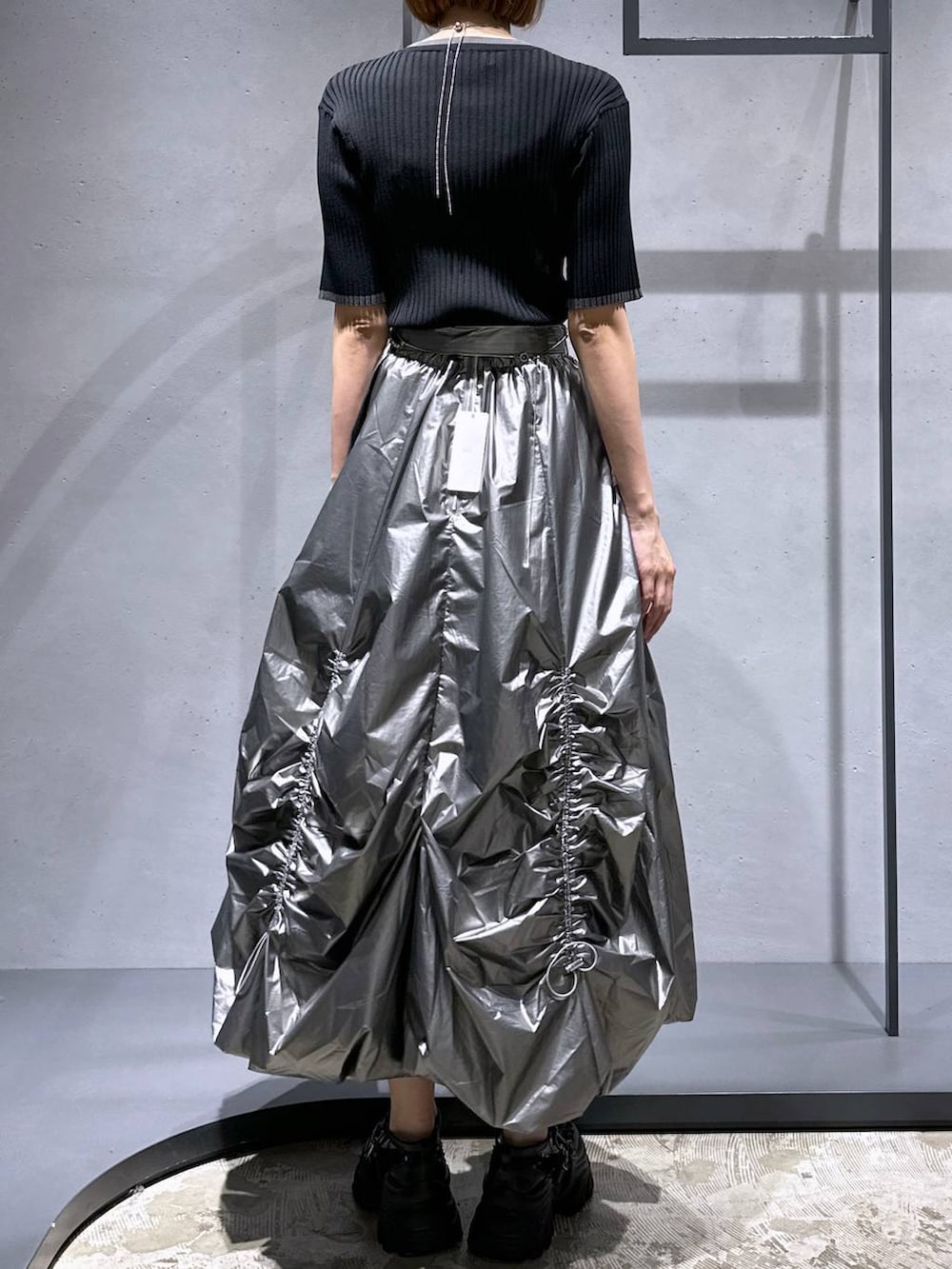 ブラック系のニット/セーター、ブラック系のスニーカー、シルバー系のスカートを着用したレディースの夏コーディネートの3枚目の写真