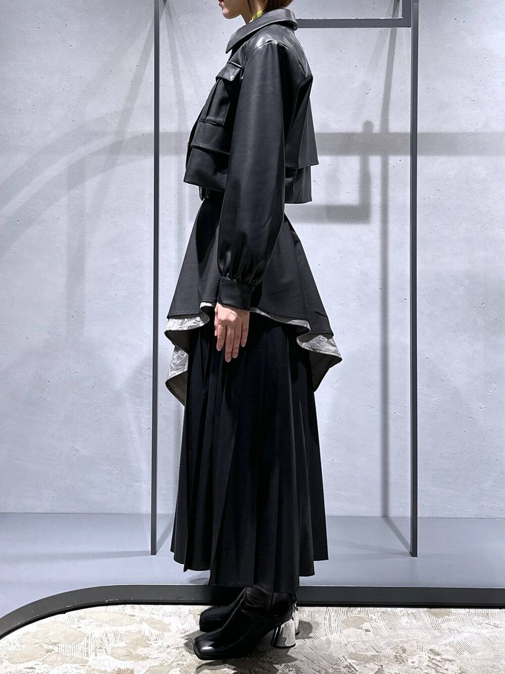 グレー系のスカート、イエロー系のニット/セーター、ブラック系のブーツを着用したレディースの秋コーディネートの2枚目の写真