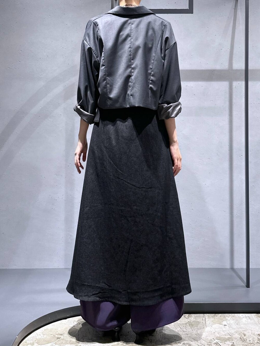 グレー系のテーラードジャケット、ブラック系のパンプス、パープル系のスラックスを着用したレディースの夏コーディネートの3枚目の写真