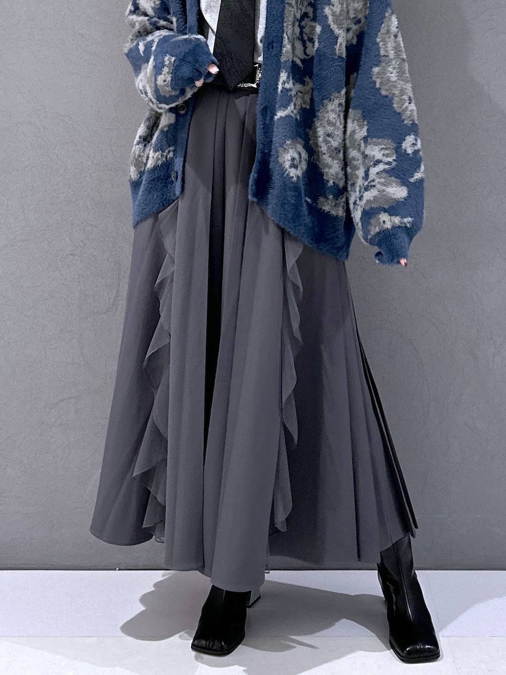 ブラック系のネクタイ、ブルー系のカーディガン/ボレロ、ブラック系のブーツを着用したレディースの秋コーディネートの6枚目の写真