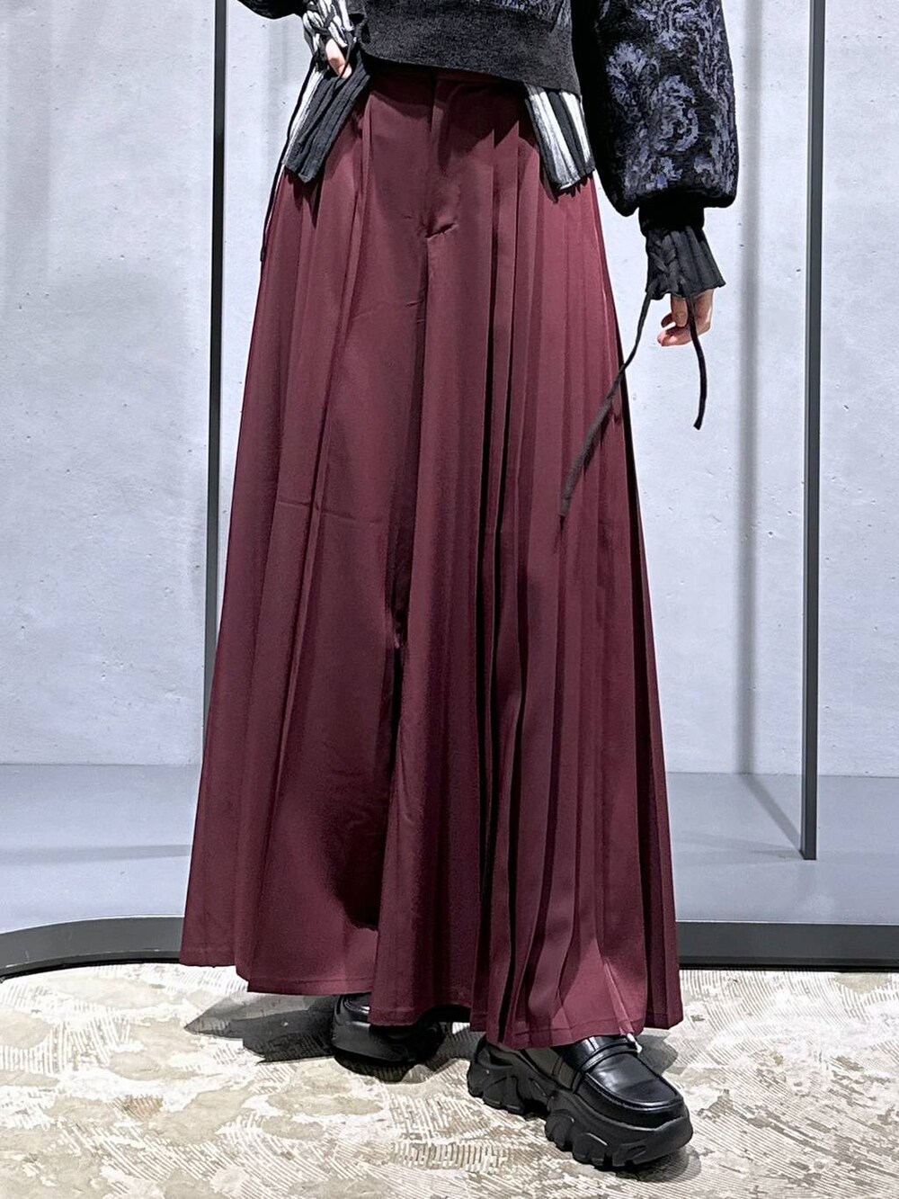 ブラック系のニット/セーター、ブラック系のローファー、レッド系のその他パンツを着用したレディースの秋コーディネートの6枚目の写真