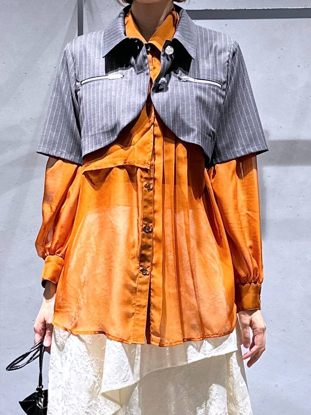 オレンジ系のシャツ/ブラウス、ホワイト系のスカート、ブラック系のブーツを着用したレディースの夏コーディネートの6枚目の写真