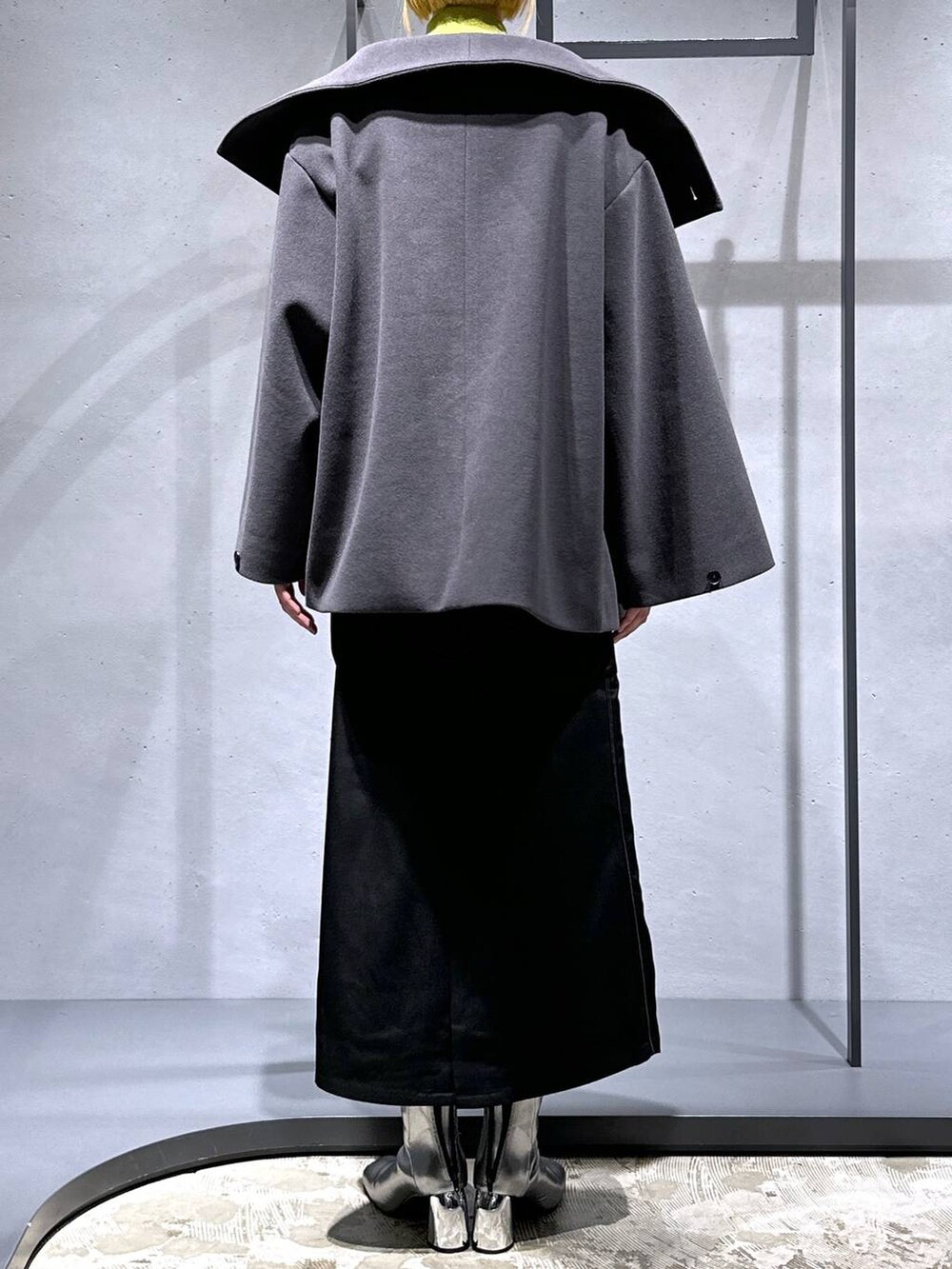 グレー系のチェスターコート、イエロー系のニット/セーター、シルバー系のブーツを着用したレディースの秋コーディネートの3枚目の写真