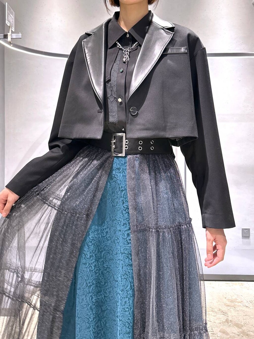 グリーン系のスカート、ブラック系のブーツ、ブラック系のシャツ/ブラウスを着用したレディースの秋コーディネートの5枚目の写真