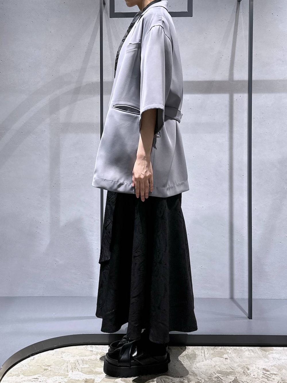 ブラック系のサンダル、ブラック系のスカート、グレー系のテーラードジャケットを着用したレディースの春コーディネートの2枚目の写真