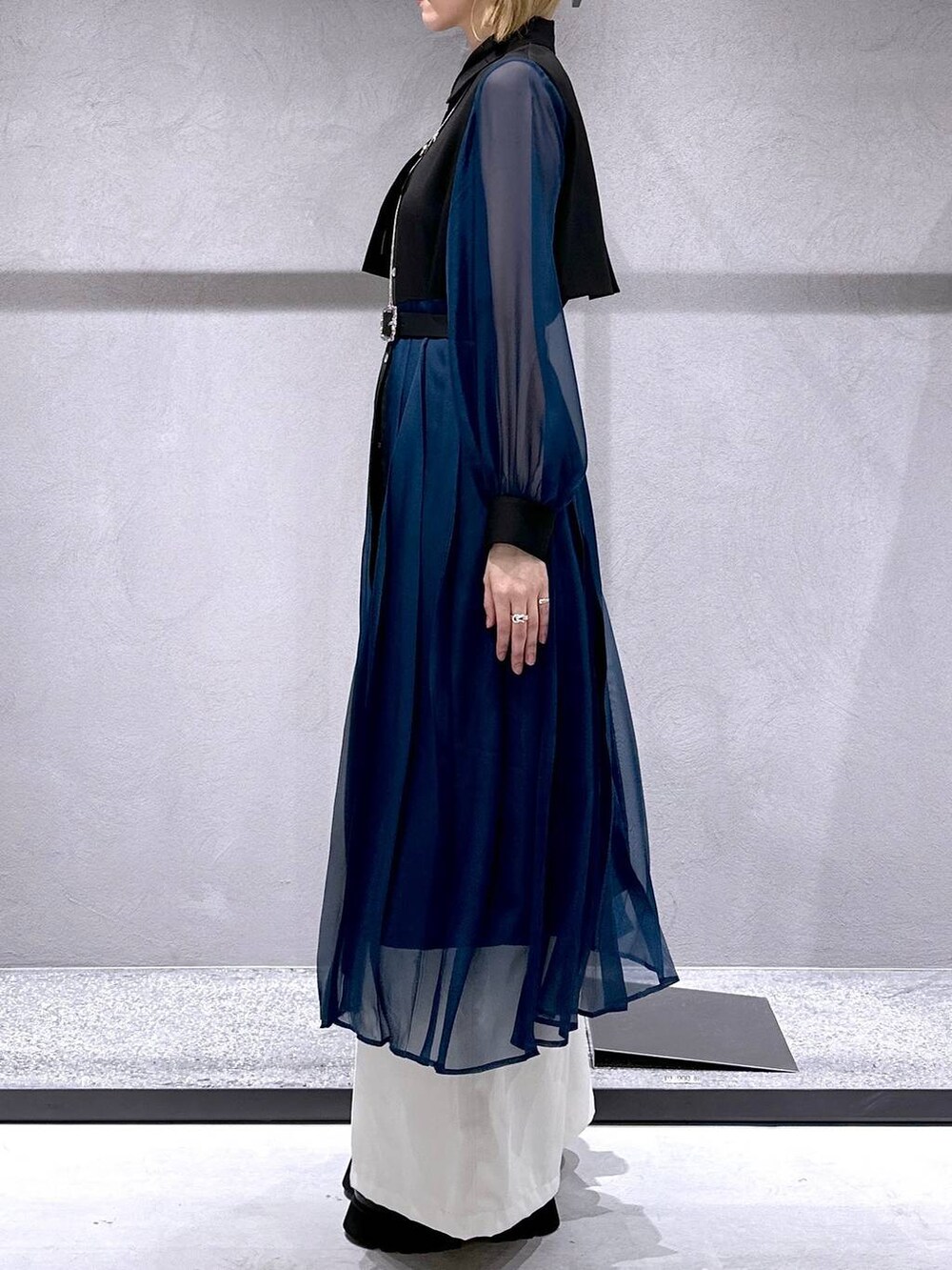 シルバー系のサンダル、ブラック系のワンピース、ホワイト系のスラックスを着用したレディースの春コーディネートの2枚目の写真