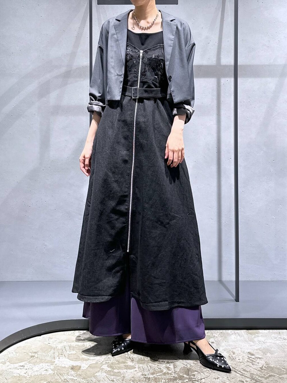 グレー系のテーラードジャケット、ブラック系のパンプス、パープル系のスラックスを着用したレディースの夏コーディネートの4枚目の写真