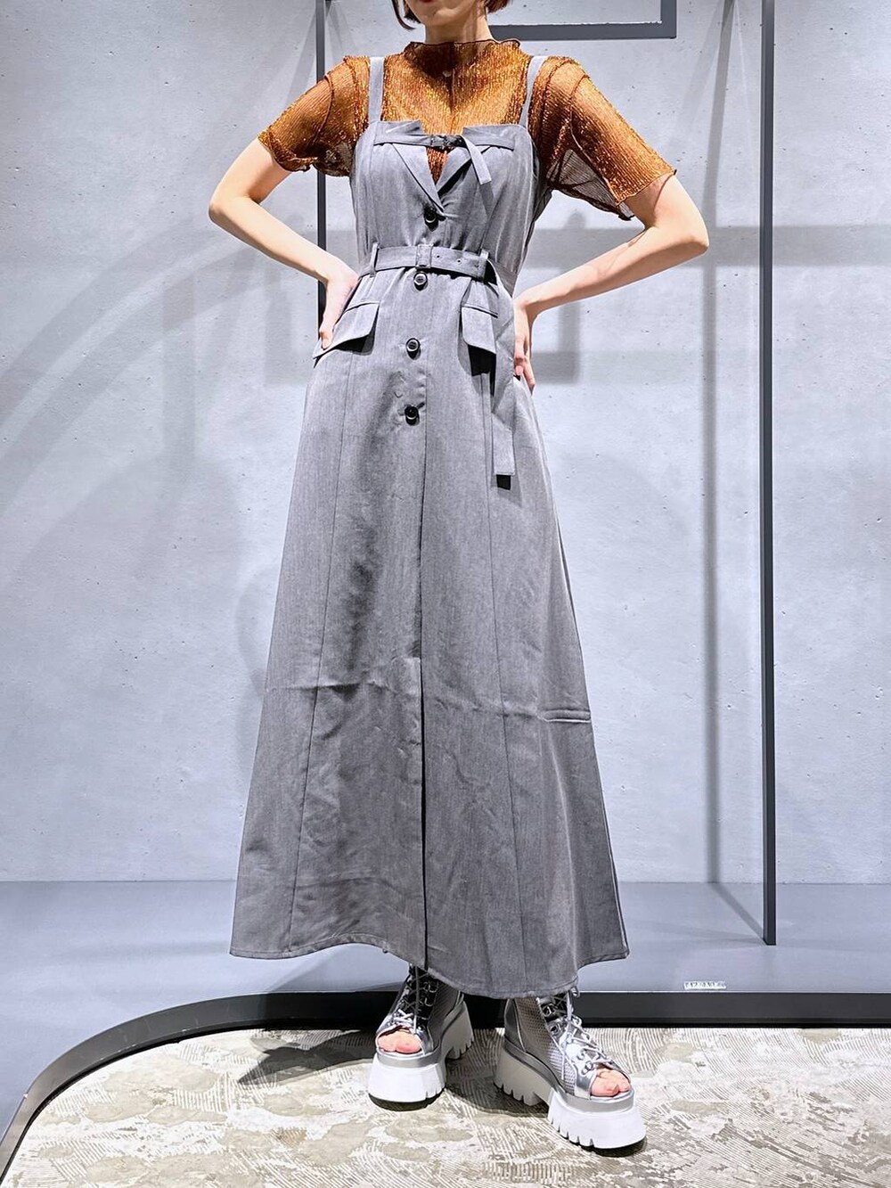 シルバー系のサンダル、オレンジ系のTシャツ/カットソー、グレー系のジャンパースカートを着用したレディースの夏コーディネートの6枚目の写真