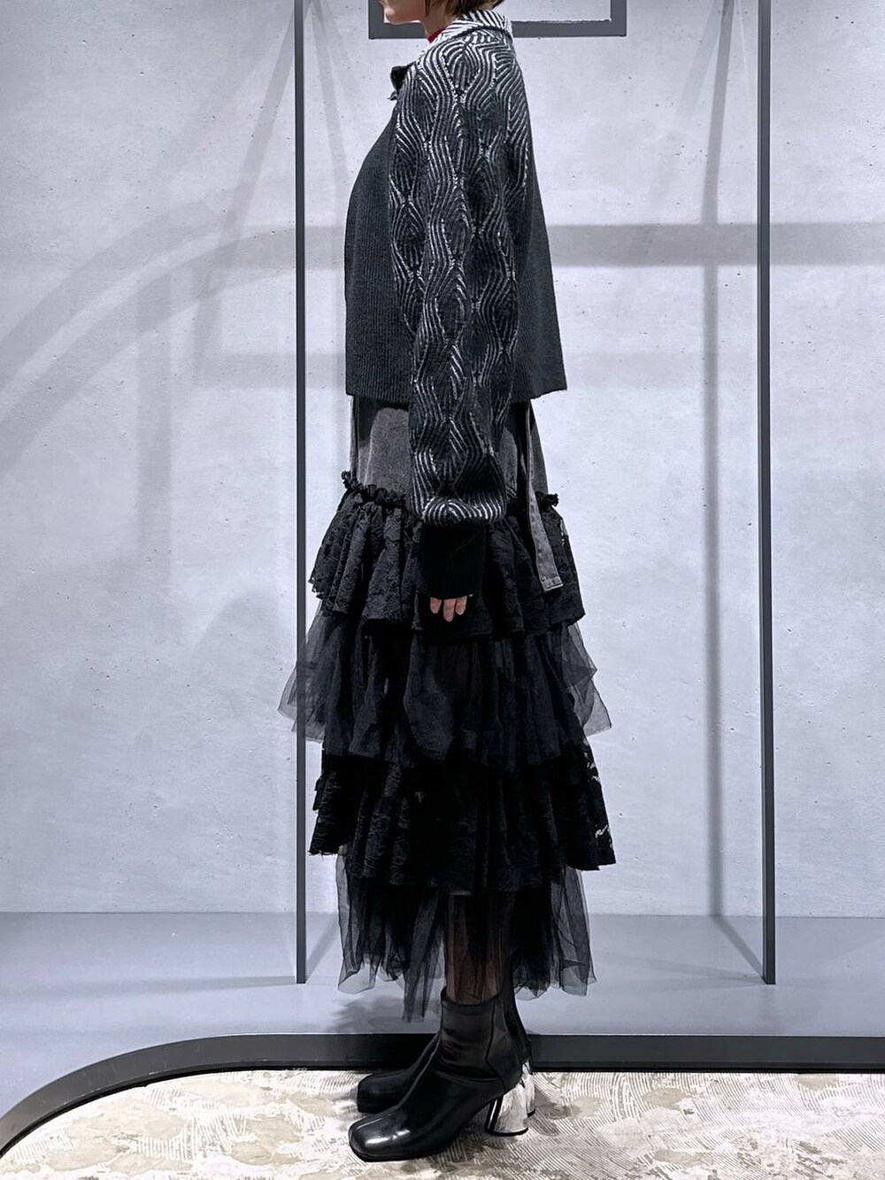 ブラック系のブーツ、ブラック系のカーディガン/ボレロ、レッド系のニット/セーターを着用したレディースの秋コーディネートの2枚目の写真