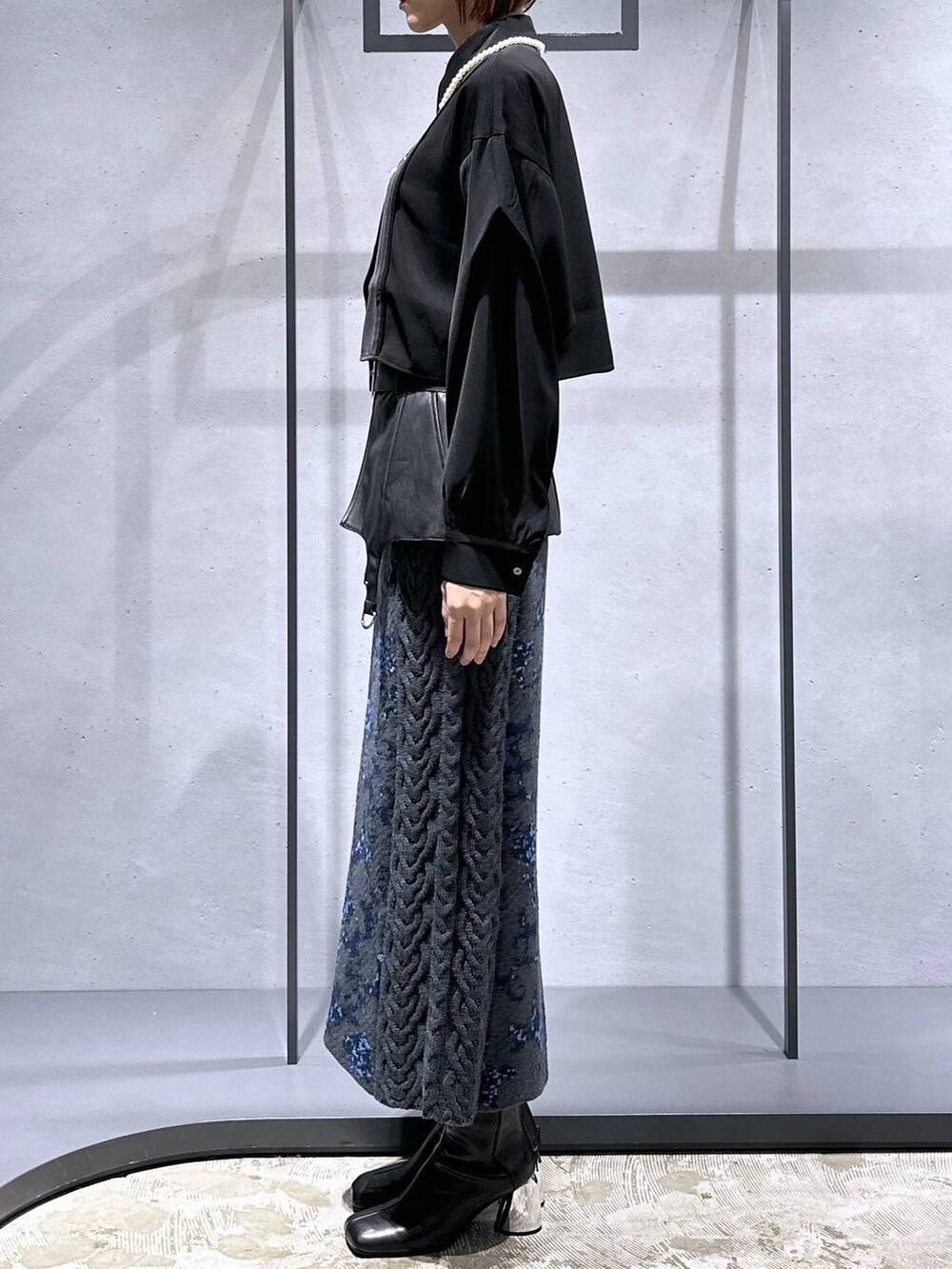 グレー系のスカート、ブラック系のブーツ、ブラック系のシャツ/ブラウスを着用したレディースの秋コーディネートの2枚目の写真