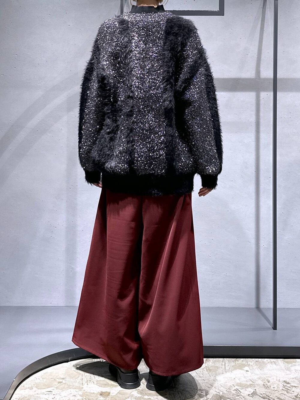 レッド系のその他パンツ、ブラック系のブーツ、ブラック系のニット/セーターを着用したレディースの冬コーディネートの3枚目の写真
