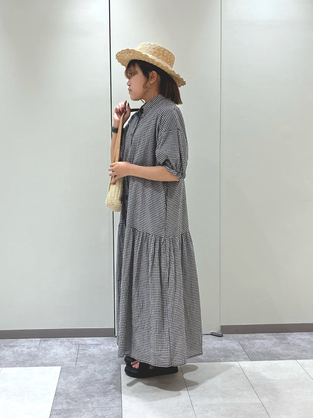 ホワイト系のハンドバッグ、ブラック系のワンピース、ブラック系のサンダルを着用したレディースの夏コーディネートの2枚目の写真