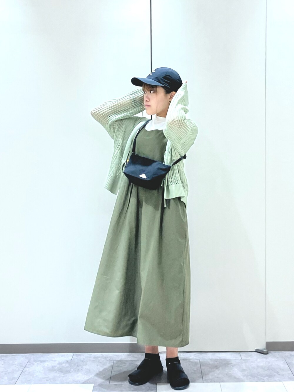 ブラック系のサンダル、グリーン系のワンピース、ブラック系のハンドバッグを着用したレディースの春コーディネートの3枚目の写真