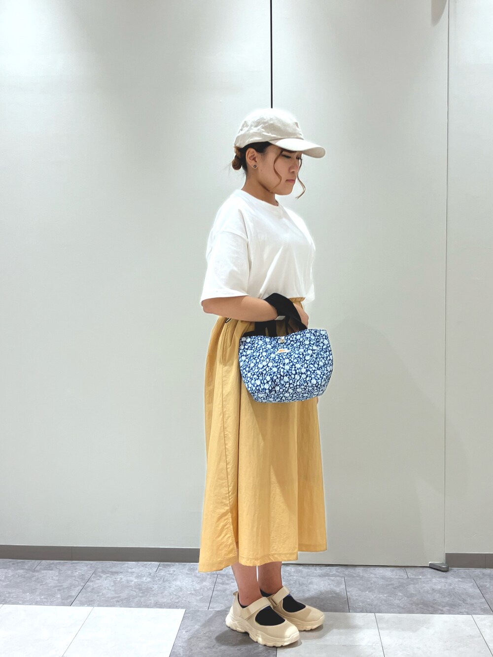 ホワイト系のワンピース、ブルー系のハンドバッグ、ベージュ系のスニーカーを着用したレディースの春コーディネートの2枚目の写真