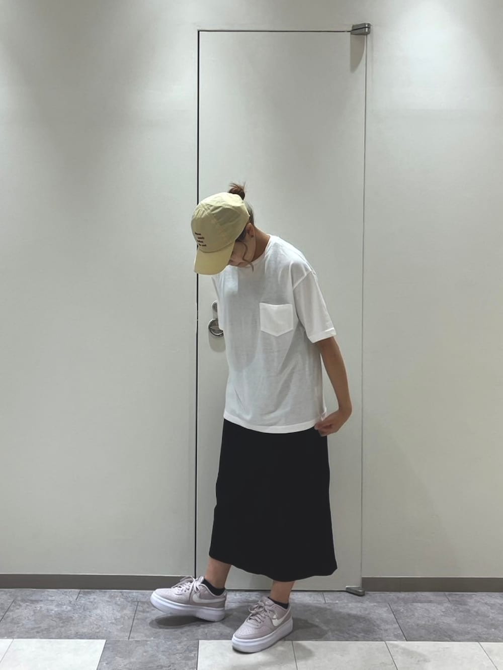 ピンク系のスニーカー、ブラック系のスカート、ホワイト系のトップスを着用したレディースの春コーディネートの3枚目の写真