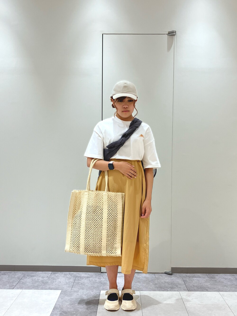 ベージュ系のスニーカー、ホワイト系のワンピース、ホワイト系のハンドバッグを着用したレディースの春コーディネートの2枚目の写真