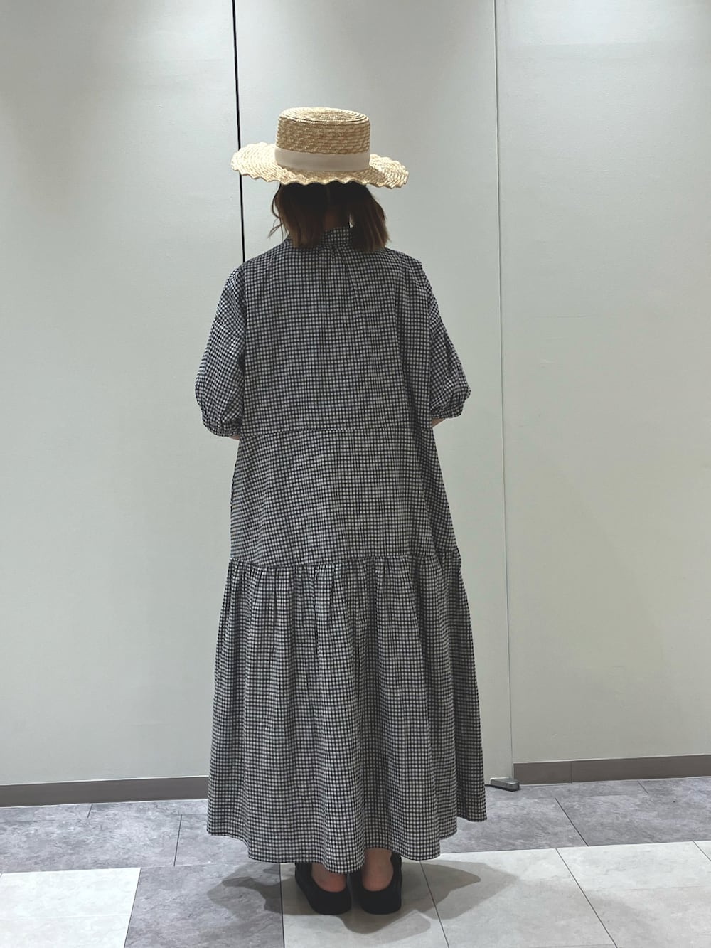 ホワイト系のハンドバッグ、ブラック系のワンピース、ブラック系のサンダルを着用したレディースの夏コーディネートの3枚目の写真