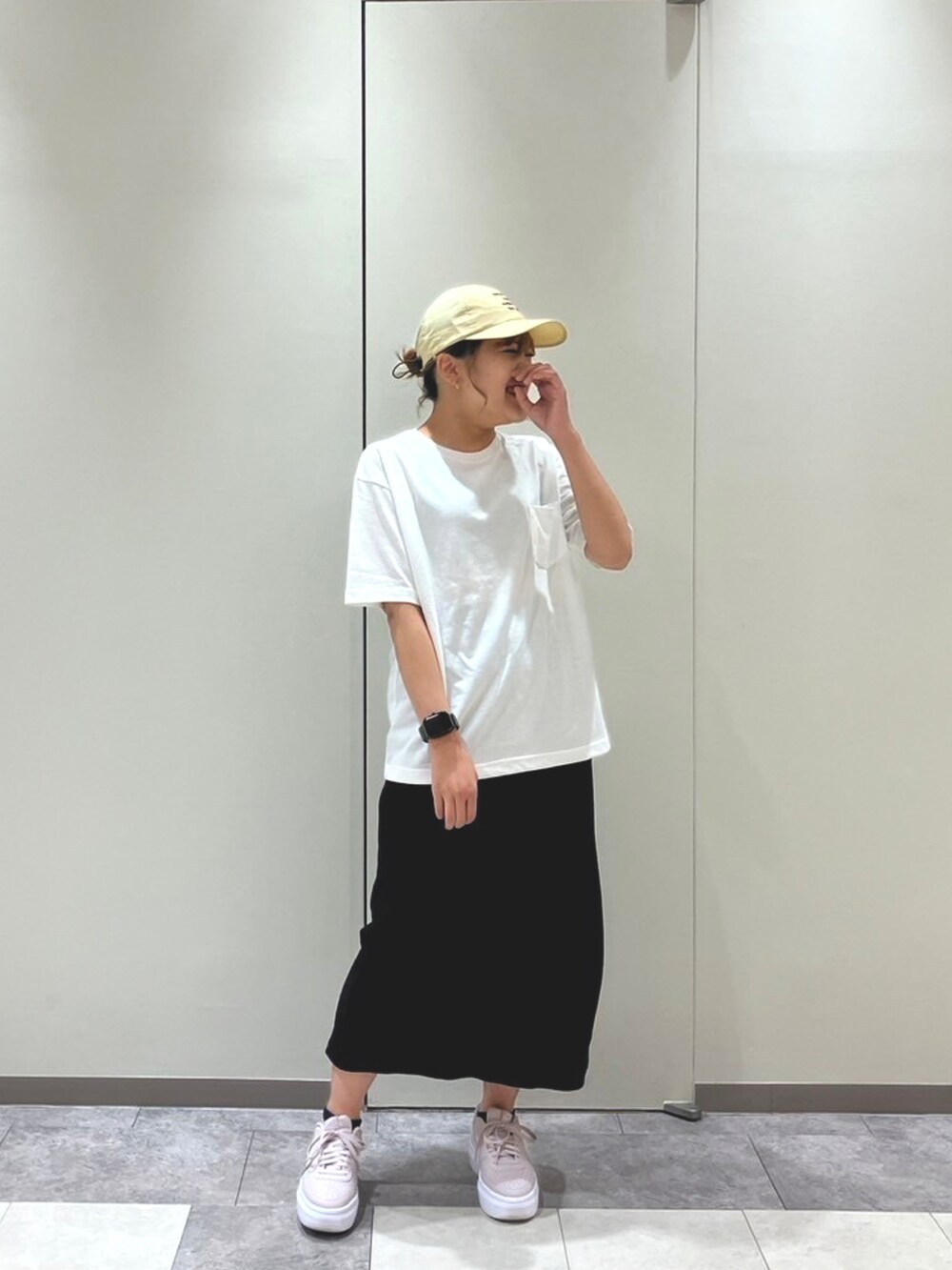 ピンク系のスニーカー、ブラック系のスカート、ホワイト系のトップスを着用したレディースの春コーディネートの2枚目の写真